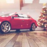 Car indoors with Christmas tree beside it